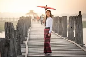 Images Dated 13th March 2016: Beautiful woman holding traditional red umbrella and walking on U Bein Bridge, Myanmar