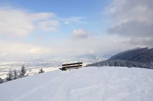 Bench on a mountain peak, snow-covered Rosenheim Basin and Chiemgau Alps at back, Leitzachtal, bei Elbach