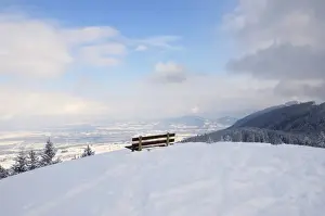 Bayern Prints: Bench on a mountain peak, snow-covered Rosenheim Basin and Chiemgau Alps at back