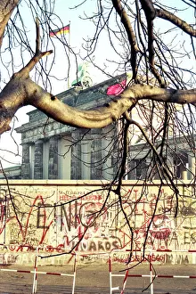 Prints of A barren tree stands in front of the graffiti-covered Berlin Wall with the neoclassical Brandenburg Gate behind it on November 12, 1989 in Berlin, Germany. (Photo by Roxanne McCann/Getty Images.) Timeless Moments: A Visual Journey Through History’s Defining Images: Berlin Wall Pepsi Commercial