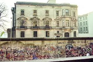 Prints of A man walks between a low wall and the graffiti-covered Berlin Wall with buildings in the background on November 12, 1989 in Berlin, Germany. (Photo by Roxanne McCann/Getty Images.) Timeless Moments: A Visual Journey Through History’s Defining Images: Berlin Wall Pepsi Commercial