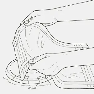 Black and white illustration of removing burnt food from electric hob using damp tea towel