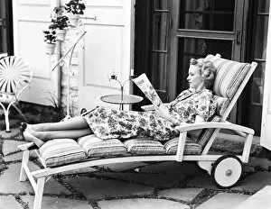 Images Dated 10th February 2006: Blonde woman reading magazine on chaise lounge