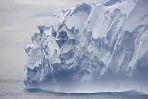 Antarctic Prints: Blue iceberg carved by waves floats in calm sea
