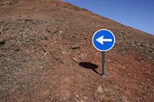Images Dated 27th December 2012: Blue sign with a white arrow pointing left, on red lava, Lanzarote, Canary Islands, Spain