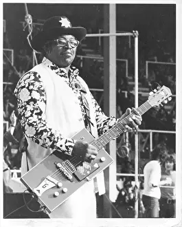 Prints of ENGLAND - CIRCA 1975: Guitarist Bo Diddley flashes peace signs as he performs onstage with his trademark square Gretsch electric guitar in circa 1975 in England Bo Diddley: Rhythm & Riffs Prints: Bo Diddley Performs In England