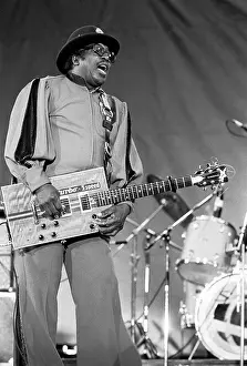 Prints of American Blues musician Bo Diddley (born Ellas Bates, 1928 - 2008) plays guitar as he performs onstage at the Petrillo bandshell in Grant Park, Chicago, Illinois, June 6, 1986 Bo Diddley: Rhythm & Riffs Prints: Bo Diddley At The Petrillo Bandshell