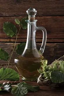 Crystal Prints: A bottle of hazelnut oil and some ripe and unripe hazelnuts (Corylus avellana) on rustic wooden boards