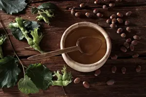 Spoon Prints: A bowl of hazelnut oil and some ripe and unripe hazelnuts (Corylus avellana) on rustic wooden boards