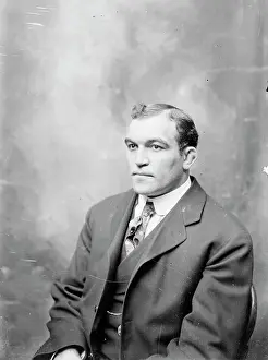 Prints of Full-length portrait of pugilist James J. Jeffries, wearing a suit, sitting at an angle in front of a backdrop in a stairwell hallway of the Chicago Daily News building in Chicago, Illinois, 1902 In the Ring: The Art of Boxing: Boxer James Jeffries