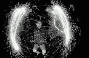 Boy (10-12) making circles with sparklers, outdoors, portrait (B&W)