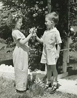 Images Dated 5th May 2006: Boy (4-5) giving girl (4-5) flowers, (B&W)