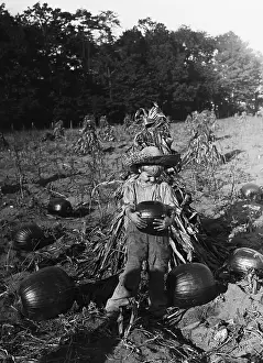 Quality Time Prints: Boy (6-7 years) carrying pumpkin in field. August 05, 1925