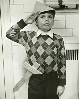 Homemade Prints: Boy (8-9) with wooden sword saluting indoors, (B&W)