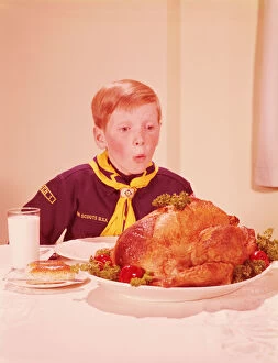 Eating Gallery: Boy in cub scout uniform looking hungrily at turkey on table. (Photo by H