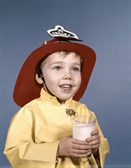Boy in fireman costume, holding a glass of milk