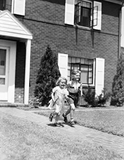 Brick Gallery: Boy and girl running down sidewalk, holding school books, going to school
