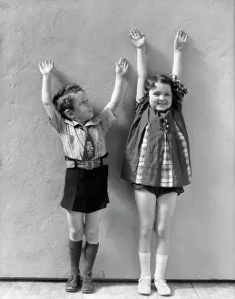 Retrofile Prints: Boy & Girl Standing Next To One Another With Arms Raised Above There Heads Girl Is Wearing A Panel Dress And White