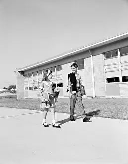 School Prints: Boy and girl walking past school, carrying books and sweaters