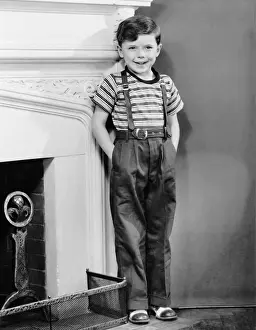 Boy leaning against wall by fireplace