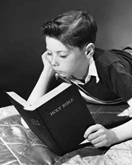 Lying On Front Prints: Boy reading Bible
