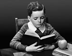 Boy reading book at desk