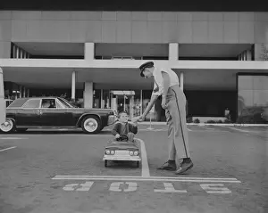 Toy Car Prints: Boy sitting in toy car giving paper to traffic police officer