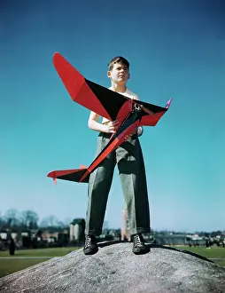 Ambition Prints: Boy Standing on Mound with Red Plane in His Hands