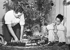 Boy Watches Dad Play with Train Set