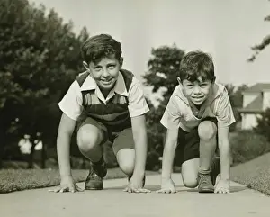 Suburbs Prints: Two boys (8-9) (12-13) ready to start running, (B&W)
