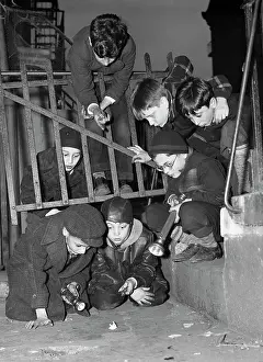 Flashlight Prints: Boys Examine Paper on the Street