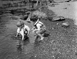 Flowing Water Gallery: Two boys playing at waters edge with toy sailboat