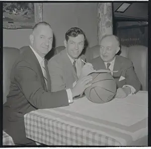Prints of (Original Caption). Irving Mitchell Felt, (left, and Ned Irish, flank Bill Bradley as Princeton Rhodes Scholar pens Knick's contract yesterday Hoops Through Time: A Visual Journey of Basketball History: Bill Bradley and Basketball Officials Sitting with Basketball
