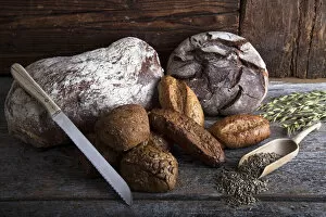 Images Dated 6th June 2012: Bread loaves, rolls and a bread knife, rye grain and ears of corn on a rustic wooden surface