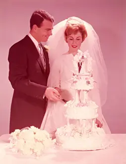 Bride and groom cutting the wedding cake. (Photo by H. Armstrong Roberts / Retrofile / Getty