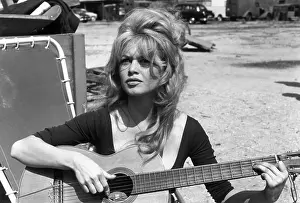 Prints of circa 1960: French actor Brigitte Bardot playing guitar while sitting on a lawn chair in an empty lot. (Photo by Hulton Archive/Getty Images) Iconic Movie Star Prints (1920s–1970s): Brigitte Bardot