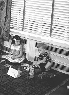 Carpet Prints: Brother (4-5) and sister (6-7) playing on floor in family room, (B&W)