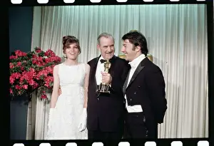 Burnett Guffey Holding His Trophy While Posing With Movie Stars