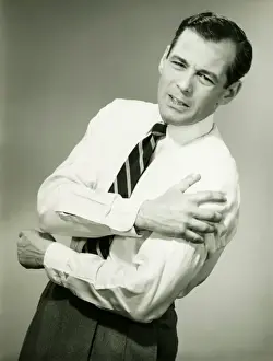 Anguished Prints: Businessman with aching arm in studio, (B&W)