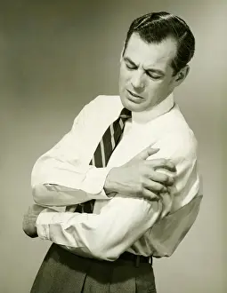 Anguished Prints: Businessman with aching arm in studio, (B&W)