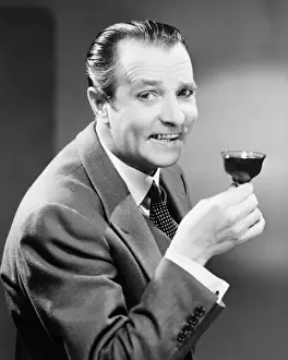 50 59 Years Prints: Businessman with glass of beverage, posing in studio, (B&W), portrait