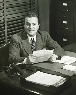 Stationery Prints: Businessman holding documents, sitting at office, (B&W)