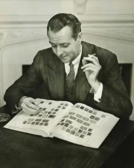 40 49 Years Prints: Businessman sitting at small table, with stamp album, (B&W)