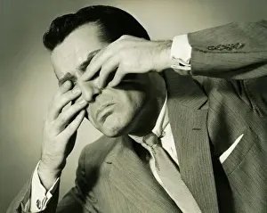 Worried Prints: Businessman in studio covering eyes with fingers, (B&W), close-up