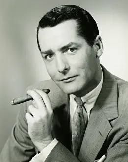 Businessman in studio holding cigar, (B&W), portrait