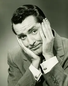 Worried Prints: Businessman in studio holding head in hands, (B&W), portrait