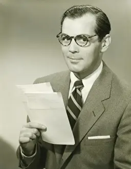 Eyewear Prints: Businessman in studio holding papers, (B&W), portrait
