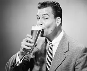 Beer Alcohol Prints: Businessman in full suit drinking beer in studio, (B&W), portrait