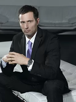 Businessman wearing a suit, sitting on a white sofa