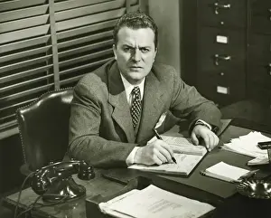 Worried Prints: Businessman writing in notepad, sitting at office, (B&W)